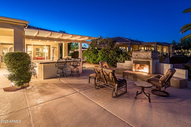 view of patio with an outdoor bar and a multi sided fireplace