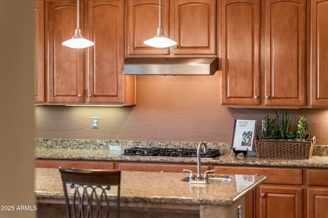 kitchen featuring sink, light stone counters, and decorative light fixtures