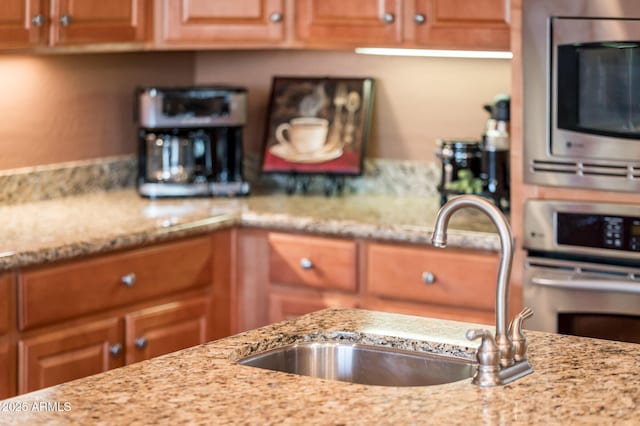 kitchen featuring stainless steel appliances, light stone countertops, and sink