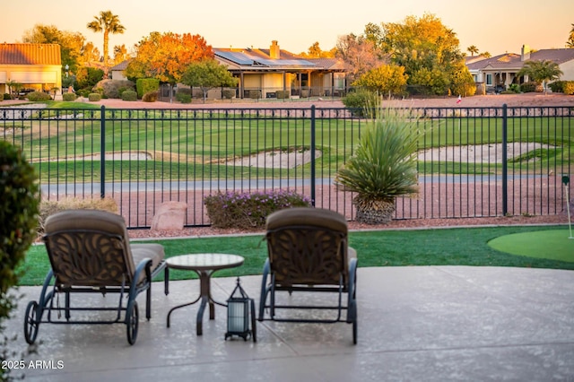 patio terrace at dusk featuring a lawn