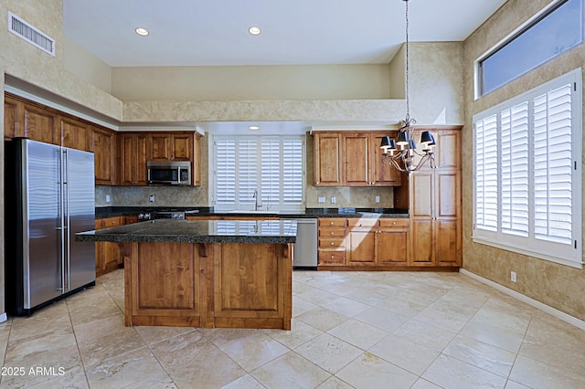 kitchen featuring visible vents, stainless steel appliances, a sink, a center island, and a notable chandelier