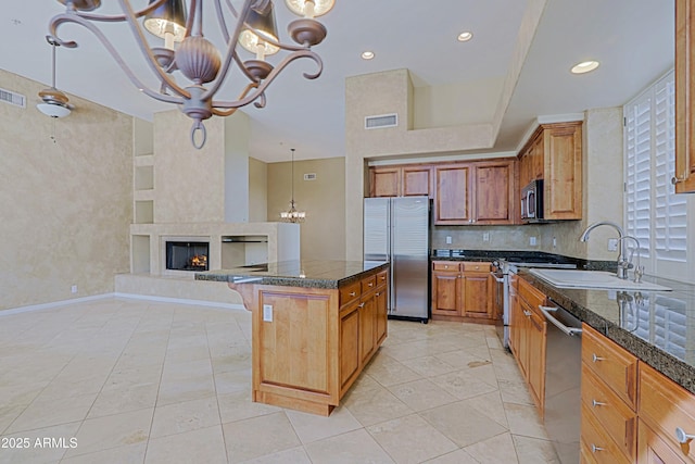 kitchen with a notable chandelier, a sink, brown cabinets, stainless steel appliances, and visible vents