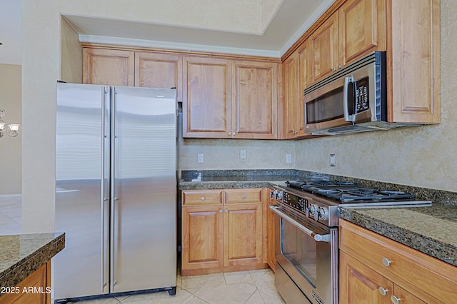 kitchen with light tile patterned flooring, brown cabinets, backsplash, and appliances with stainless steel finishes