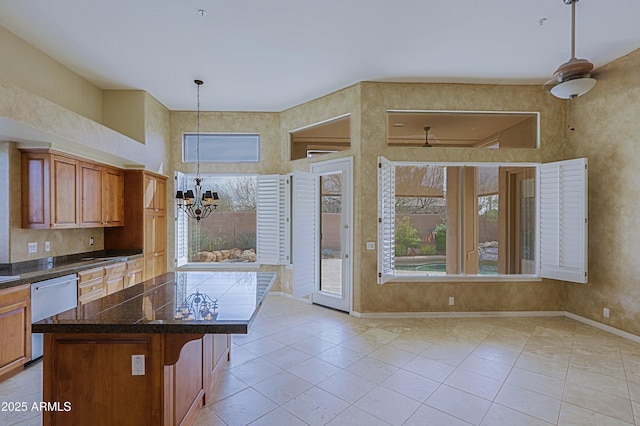 kitchen featuring a notable chandelier, a kitchen bar, dishwasher, brown cabinetry, and baseboards