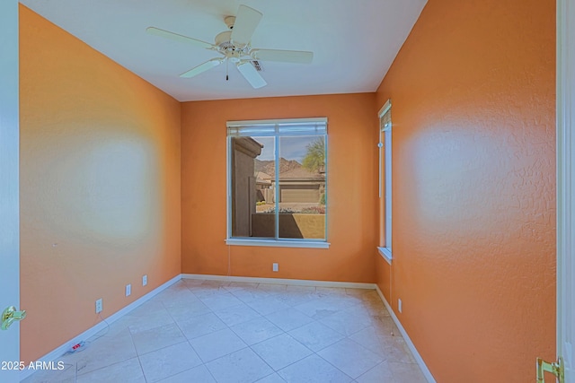 spare room featuring a ceiling fan, light tile patterned floors, and baseboards