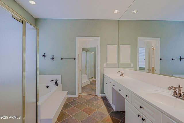 bathroom featuring a sink, a garden tub, a shower stall, recessed lighting, and double vanity