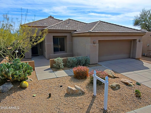 view of front of house with a tiled roof, stucco siding, an attached garage, and concrete driveway
