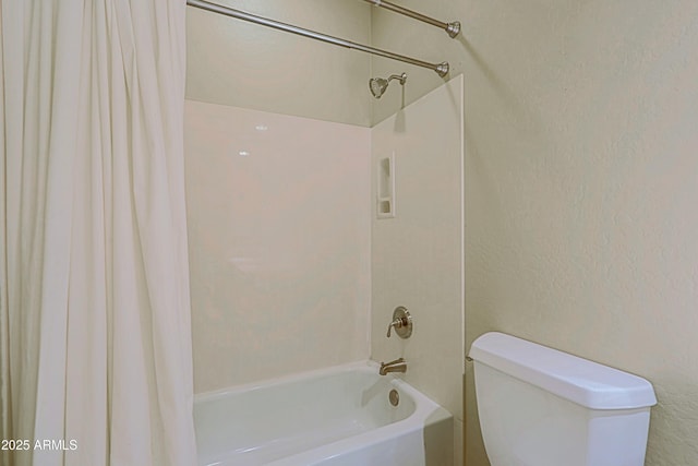 bathroom with shower / bath combo with shower curtain, a textured wall, and toilet