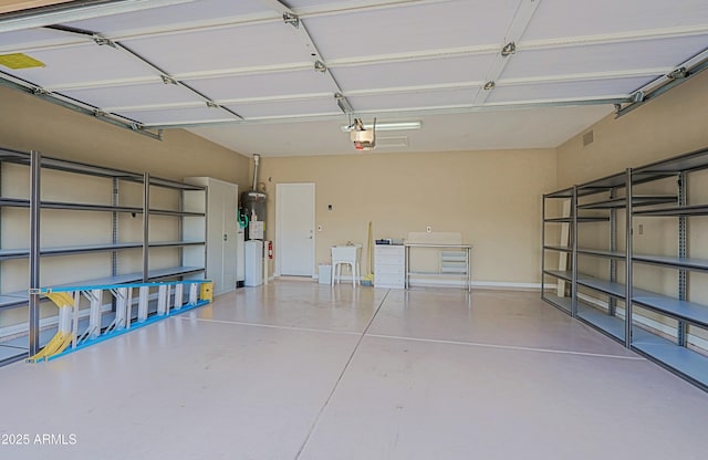 garage with a sink, strapped water heater, visible vents, and a garage door opener