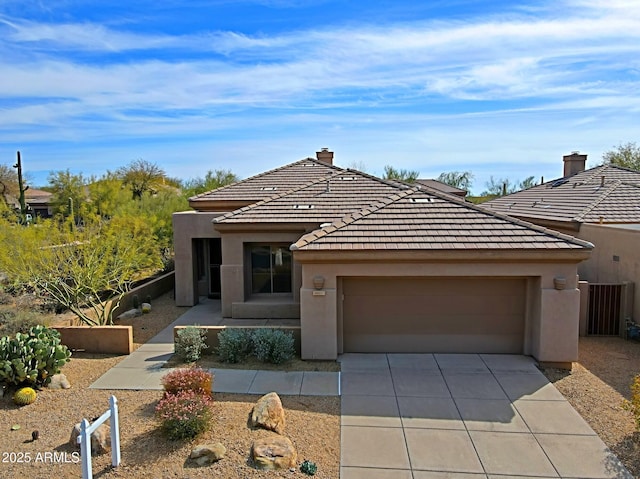 view of front of house with an attached garage, a chimney, stucco siding, a tile roof, and driveway