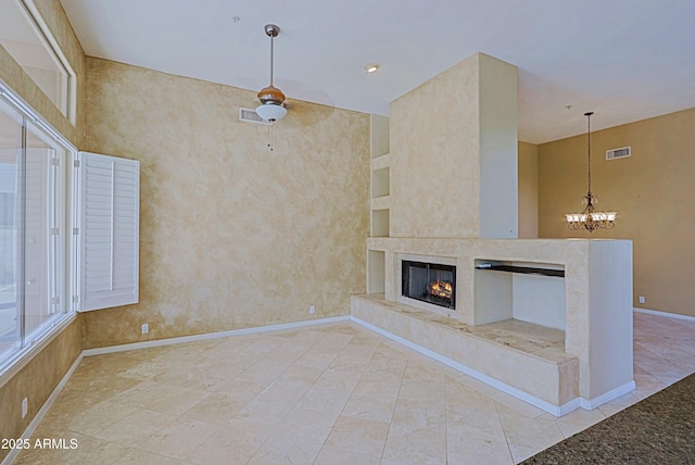 unfurnished living room with baseboards, visible vents, an inviting chandelier, and a premium fireplace