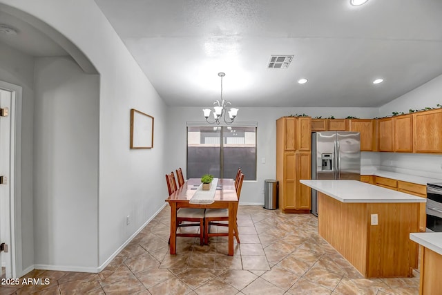 kitchen with visible vents, a notable chandelier, stainless steel appliances, arched walkways, and light countertops