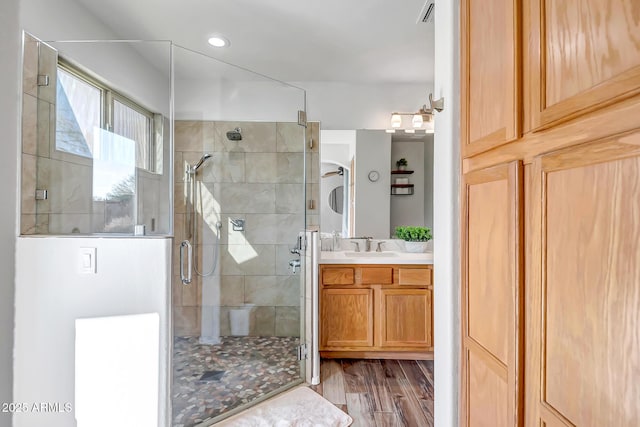 bathroom with vanity, a shower stall, wood finished floors, and visible vents