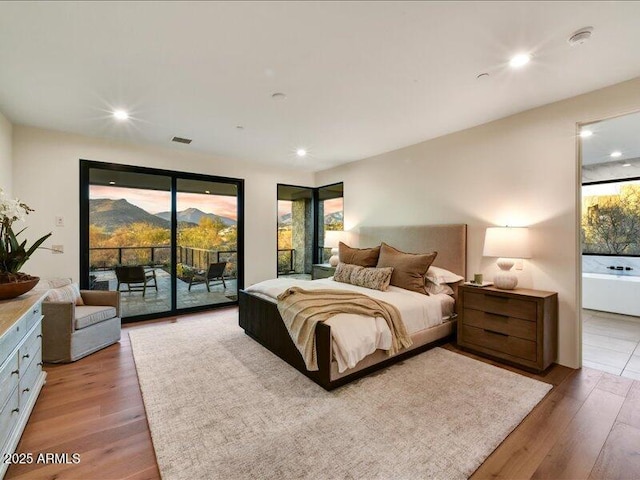 bedroom featuring multiple windows, hardwood / wood-style flooring, and access to outside