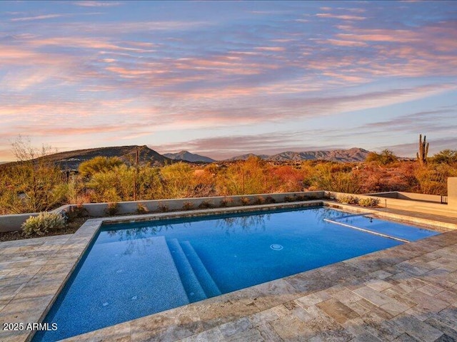 pool at dusk with a mountain view and a patio