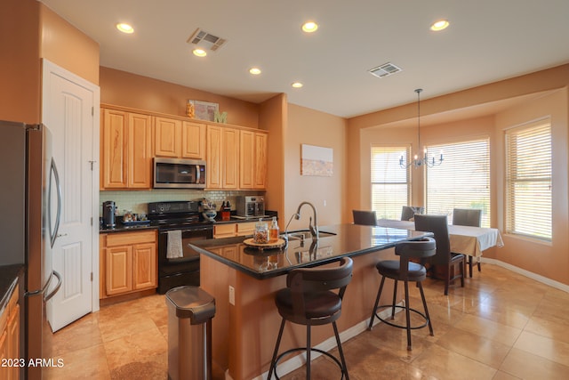 kitchen with an inviting chandelier, tasteful backsplash, an island with sink, pendant lighting, and appliances with stainless steel finishes