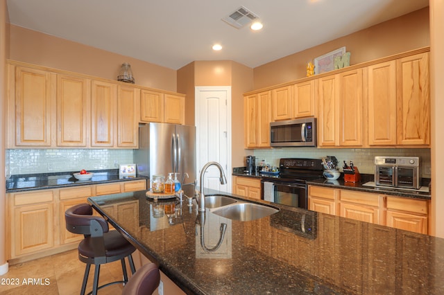 kitchen with backsplash, dark stone countertops, sink, and stainless steel appliances