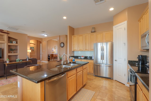 kitchen with sink, decorative backsplash, an island with sink, light brown cabinetry, and appliances with stainless steel finishes