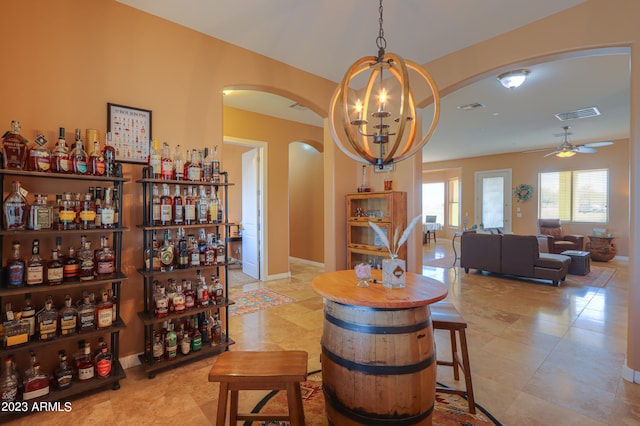 interior space with ceiling fan with notable chandelier, light tile patterned flooring, and indoor bar