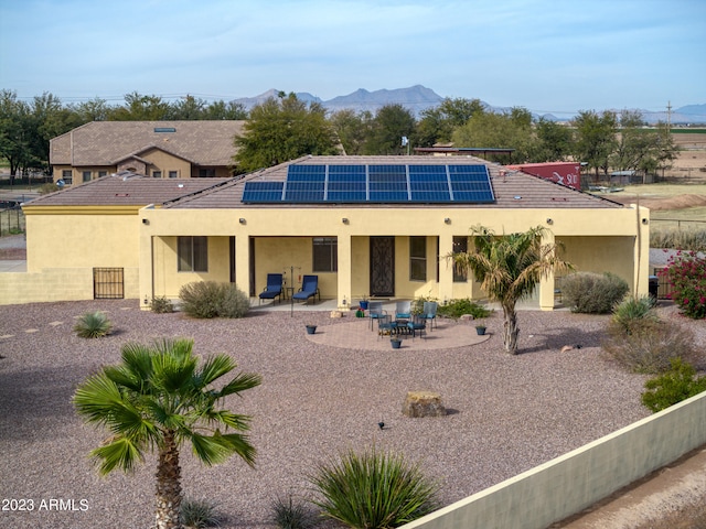 back of property with a mountain view, solar panels, and a patio area