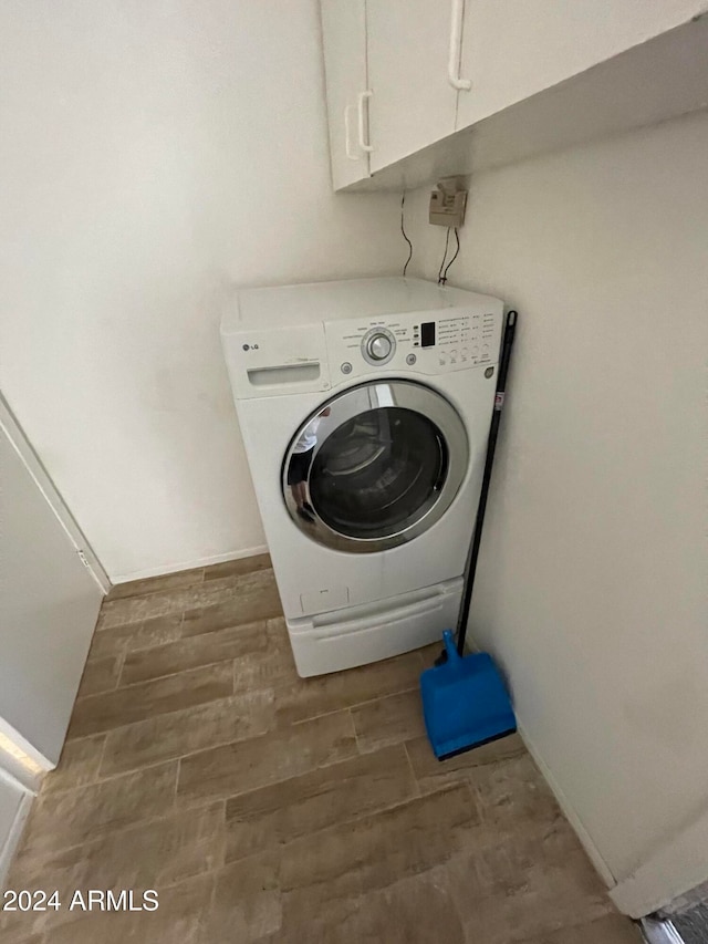 laundry area with dark hardwood / wood-style flooring, washer / clothes dryer, and cabinets