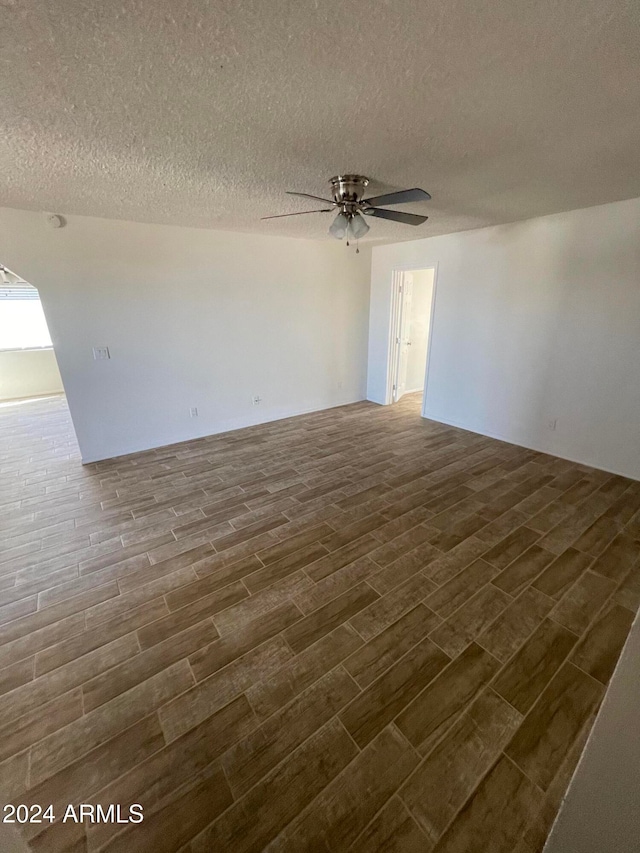 unfurnished room featuring ceiling fan, a textured ceiling, and dark hardwood / wood-style floors