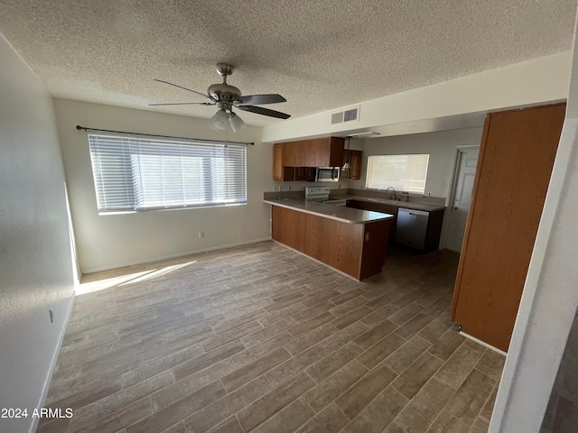 kitchen with stainless steel appliances, hardwood / wood-style flooring, a textured ceiling, and kitchen peninsula