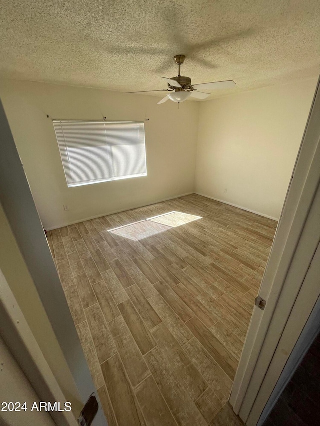 empty room featuring hardwood / wood-style floors, ceiling fan, and a textured ceiling