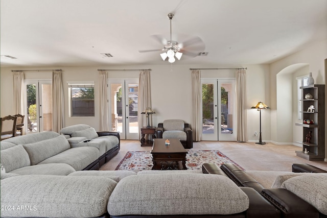 living room featuring french doors, ceiling fan, a healthy amount of sunlight, and light carpet