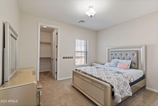 bedroom with a walk in closet, a closet, and light colored carpet