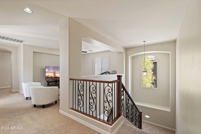 corridor featuring a notable chandelier and light colored carpet