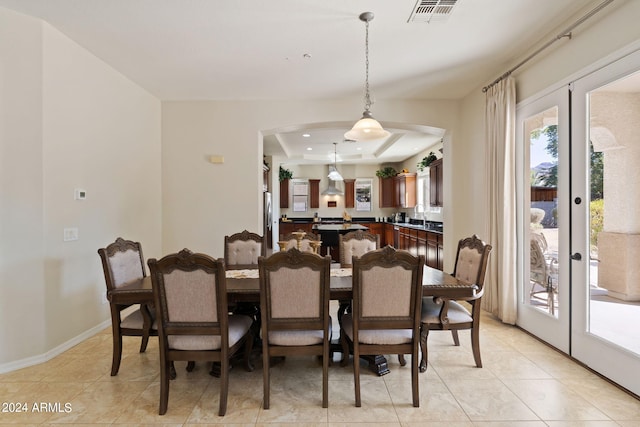 tiled dining room with french doors, a tray ceiling, and sink