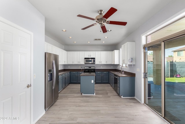 kitchen with stainless steel appliances, white cabinetry, sink, light hardwood / wood-style floors, and a center island