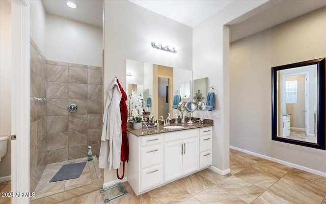 bathroom featuring a tile shower, tile patterned flooring, and vanity