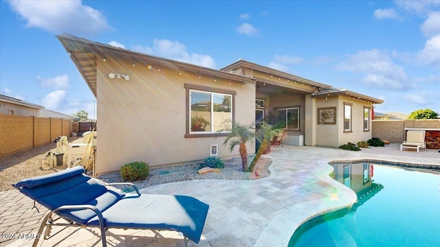 rear view of house featuring a fenced in pool and a patio area