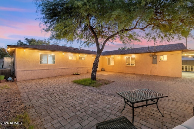 back house at dusk with a patio area and central AC unit