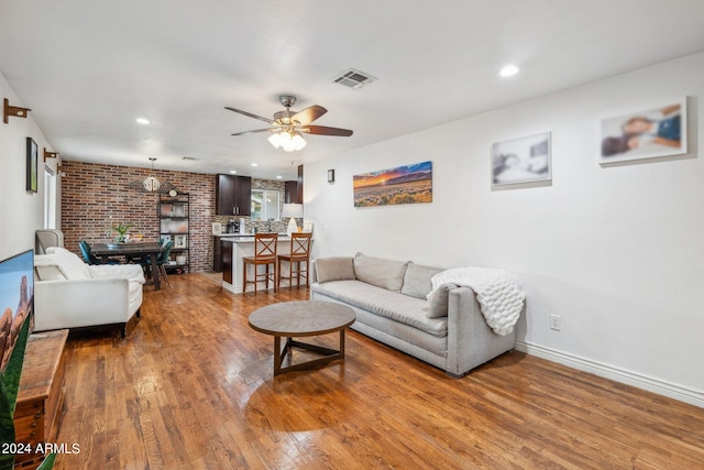 living room featuring brick wall, hardwood / wood-style floors, and ceiling fan