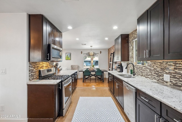 kitchen with sink, decorative light fixtures, light hardwood / wood-style flooring, stainless steel appliances, and decorative backsplash