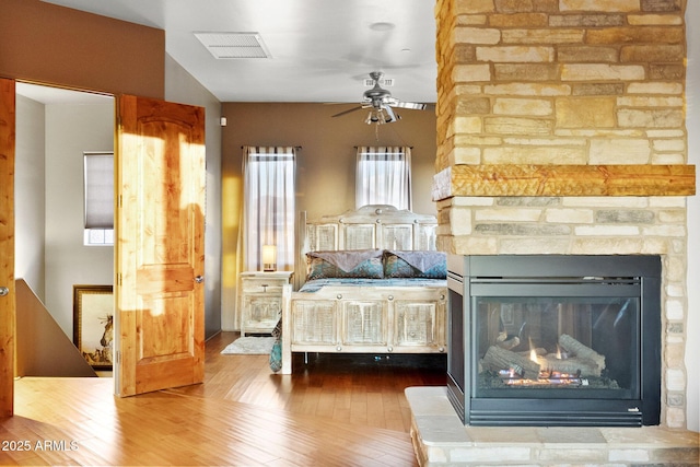 bedroom featuring hardwood / wood-style floors and a stone fireplace