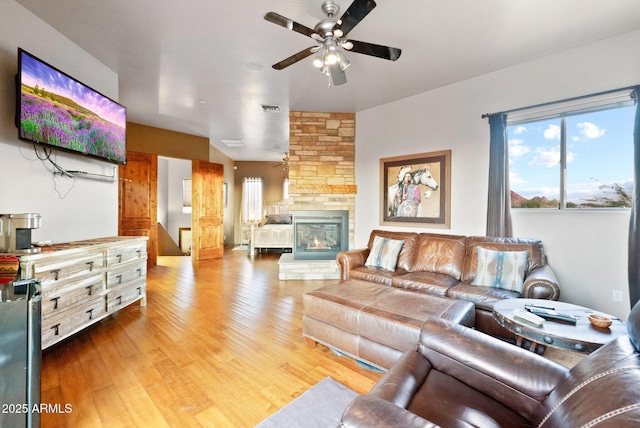 living room featuring ceiling fan, hardwood / wood-style floors, and a fireplace