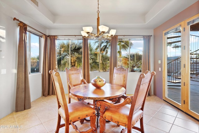 dining room with light tile patterned flooring, an inviting chandelier, a healthy amount of sunlight, and a tray ceiling