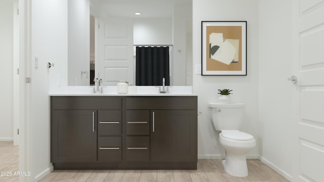 full bath with double vanity, toilet, baseboards, and wood finished floors