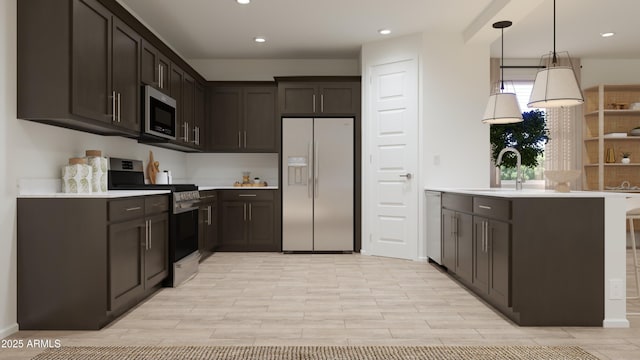 kitchen with dark brown cabinets, light countertops, a sink, decorative light fixtures, and stainless steel appliances