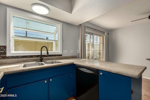 kitchen with sink, hardwood / wood-style flooring, dishwasher, blue cabinets, and kitchen peninsula