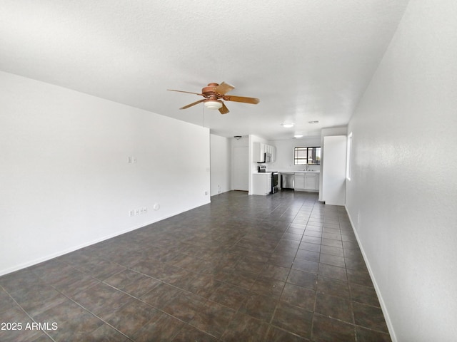 unfurnished living room with sink, dark tile patterned flooring, and ceiling fan