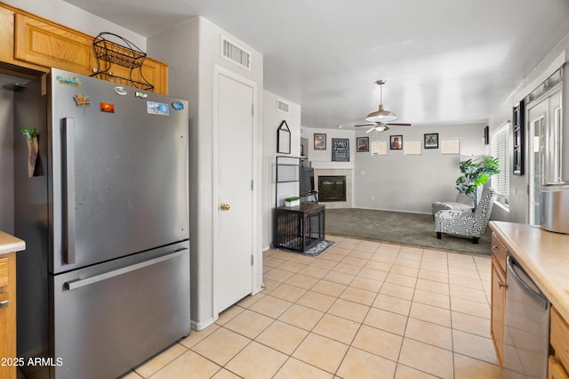 1374 E 10th Pl, Casa Grande, AZ 85122 - kitchen with stainless steel appliances, a ceiling fan, light carpet, light countertops, and a fireplace