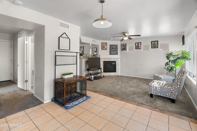 1374 E 10th Pl, Casa Grande, AZ 85122 - living room featuring light carpet, a ceiling fan, a tiled fireplace, and light tile patterned flooring