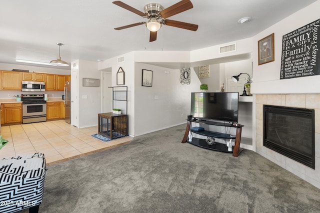1374 E 10th Pl, Casa Grande, AZ 85122 - living room with light carpet, ceiling fan, a tiled fireplace, and light tile patterned floors