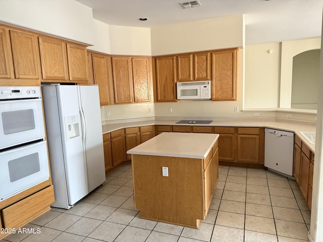 kitchen with white appliances, a center island, sink, and light tile patterned floors