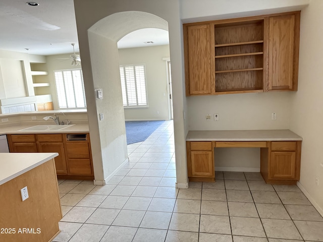 kitchen featuring built in desk, sink, light tile patterned floors, ceiling fan, and white dishwasher